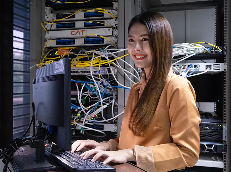 Technician performing maintenance tasks in a server room rack